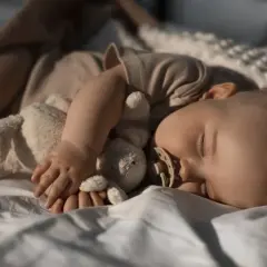 Słodki sen maluszka z przytulanką i smoczkiem. Cudowne chwile, kiedy dziecko przesypia noc.