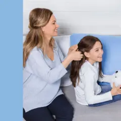 Mama czesze córkę, która trzyma misia. Rodzina spędza czas razem, może planują śmieszne zadania do wykonania dla dzieci.