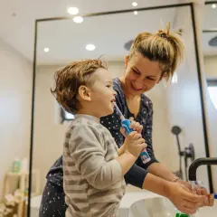 Mama pomaga dziecku myć zęby, by pozbyć się nieprzyjemnego zapachu z ust.