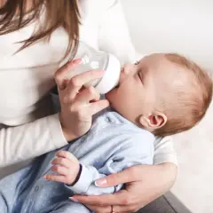 Mama karmi butelką noworodka, pokazując jak karmic butelka noworodka.