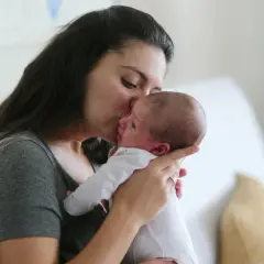 Ciepły uścisk mamy dla jej 6 tygodniowego dziecka. Delikatny pocałunek na czole maluszka.