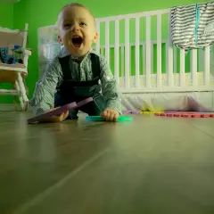 Radosny maluch na podłodze, kiedy dziecko zaczyna pełzać, bawi się kolorowymi puzzlami.