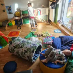 Dzieci bawią się na domowym torze przeszkód: tunel, ścieżka sensoryczna, ścianka wspinaczkowa i bujak.