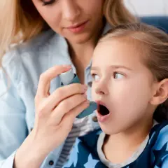 Mama pomaga córce z astmą wczesnodziecięcą użyć inhalatora.