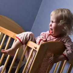 Małe dziecko wierci się w nocy, płacząc w łóżeczku.