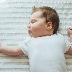 Słodki niemowlak śpi z rękami do góry, jakby chciał objąć cały świat.