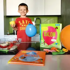 Chłopiec z balonem i cytryną przygotowuje eksperymenty w przedszkolu. Obok książki o balonach i wodzie.