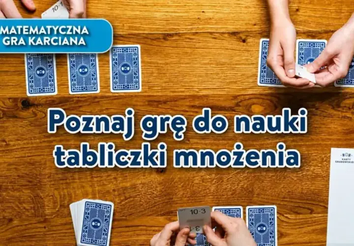 Gra karciana "Poznaj grę do nauki tabliczki mnożenia" na drewnianym stole. Dłonie trzymają karty z działaniami.