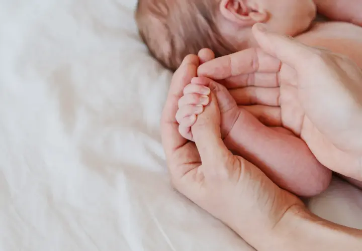 Delikatna dłoń rodzica obejmuje maleńką rączkę niemowlęcia. Octenisept na trądzik niemowlęcy to rozwiązanie dla wrażliwej skóry.