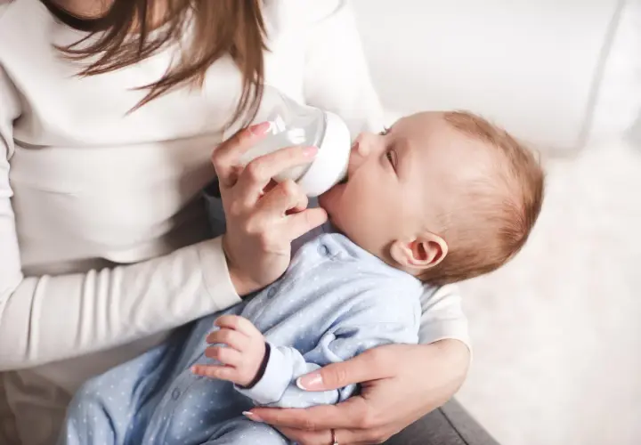 Mama karmi butelką noworodka, pokazując jak karmic butelka noworodka.
