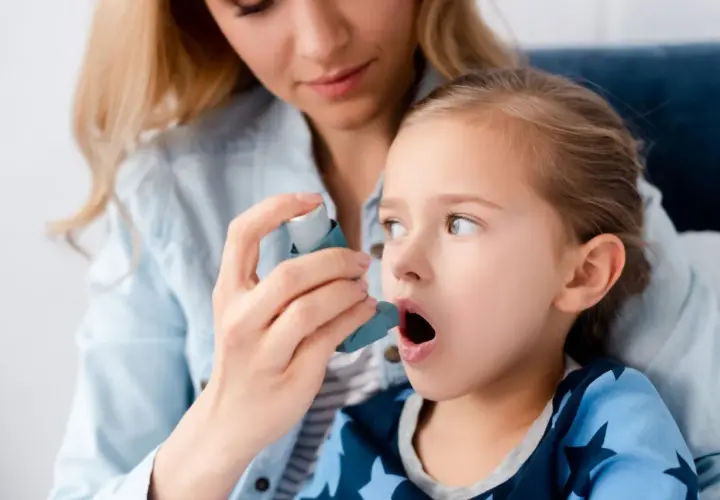 Mama pomaga córce z astmą wczesnodziecięcą użyć inhalatora.
