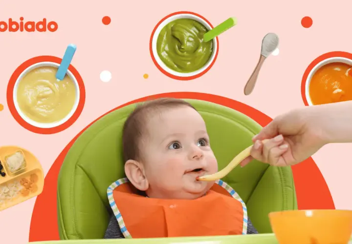 Uśmiechnięte dziecko w krzesełku do karmienia podczas rozszerzania diety. Na stole puree z warzyw i owoców, makaron.