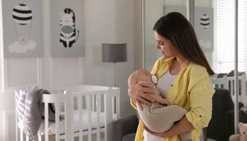 Mama tuli dziecko do snu w body i spodniach, pokazując, jak ubrać dziecko do snu bez śpiworku.