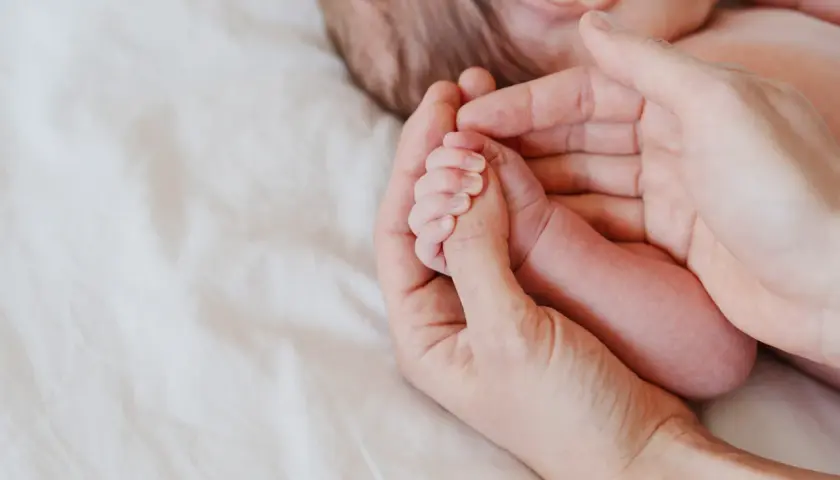 Delikatna dłoń rodzica obejmuje maleńką rączkę niemowlęcia. Octenisept na trądzik niemowlęcy to rozwiązanie dla wrażliwej skóry.