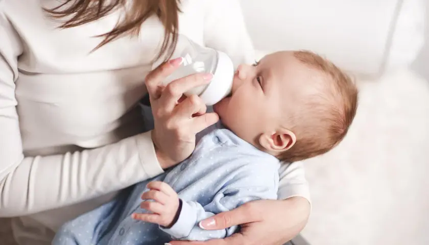 Mama karmi butelką noworodka, pokazując jak karmic butelka noworodka.