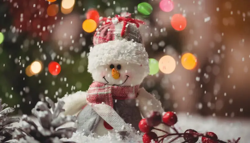 Uroczy bałwanek w czapce i szaliku, otoczony sztucznym śniegiem i świątecznymi lampkami. Idealny pomysł, jak zrobić sztuczny śnieg na święta!