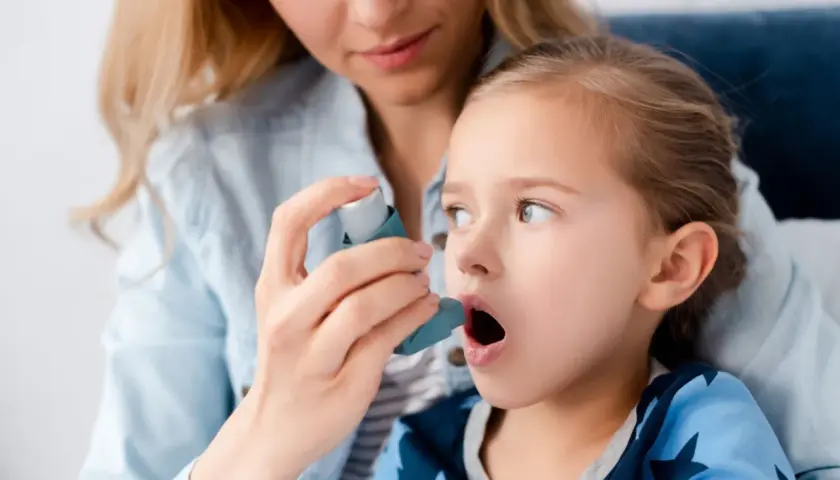 Mama pomaga córce z astmą wczesnodziecięcą użyć inhalatora.