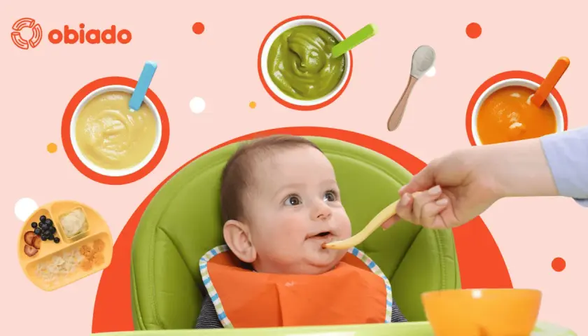 Uśmiechnięte dziecko w krzesełku do karmienia podczas rozszerzania diety. Na stole puree z warzyw i owoców, makaron.
