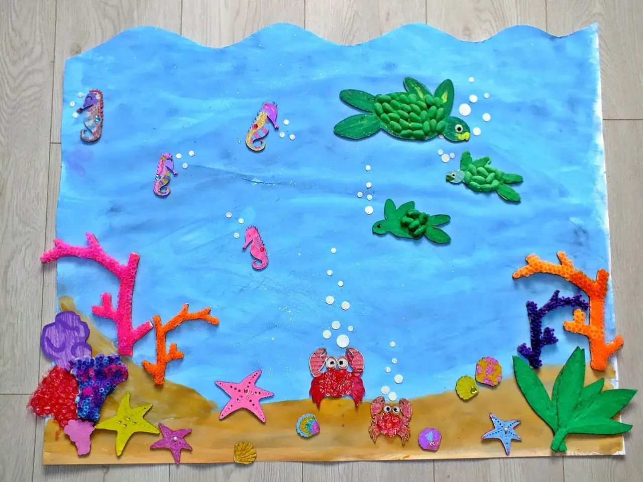 Kolorowa praca plastyczna "Ocean" z konikami morskimi, żółwiami, krabami i koralowcami.