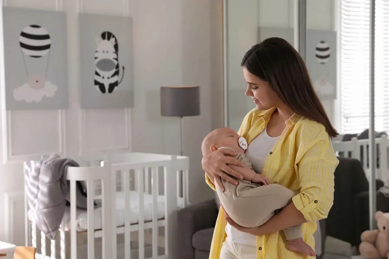 Mama tuli dziecko do snu w body i spodniach, pokazując, jak ubrać dziecko do snu bez śpiworku.