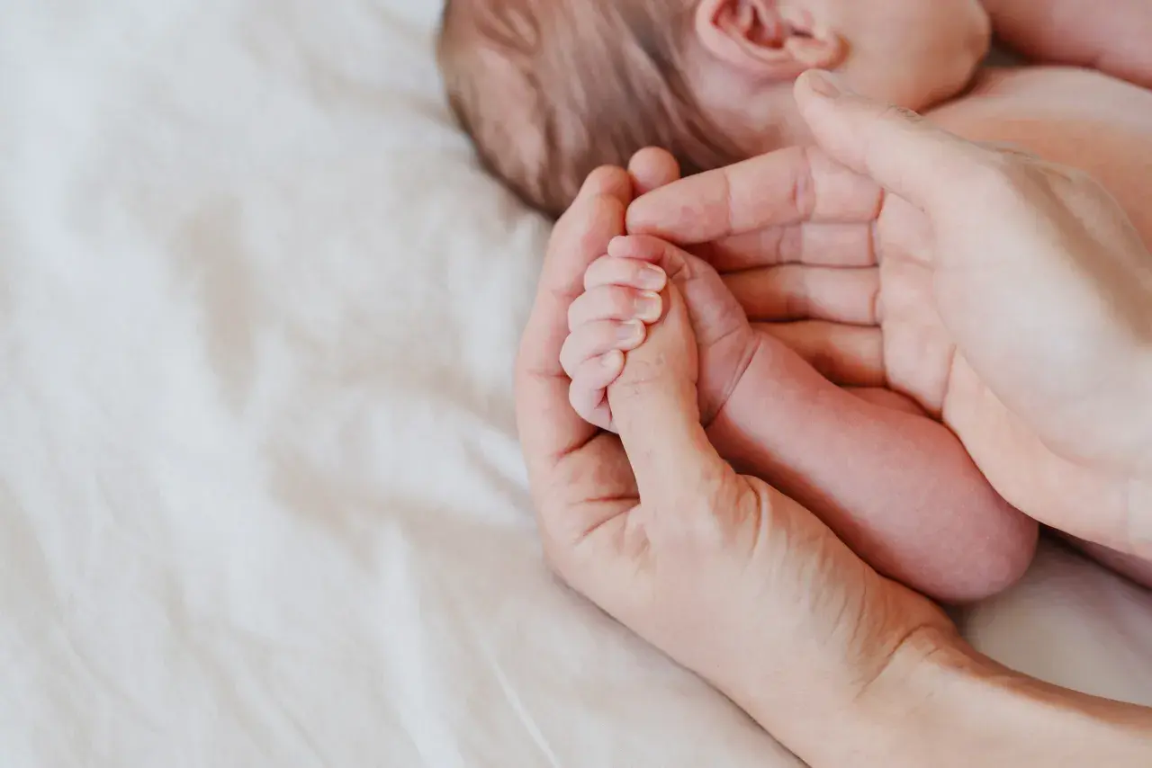 Delikatna dłoń rodzica obejmuje maleńką rączkę niemowlęcia. Octenisept na trądzik niemowlęcy to rozwiązanie dla wrażliwej skóry.