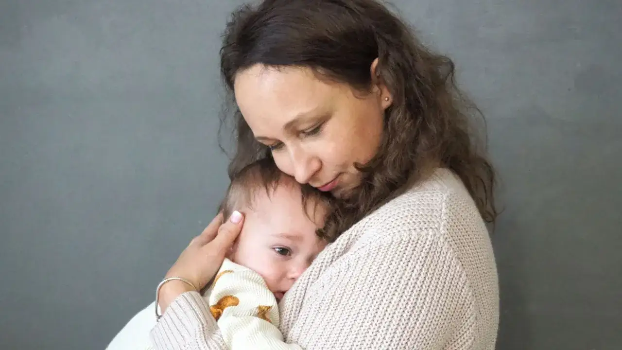Mama tuli tulą do siebie dziecko, łagodząc lęk separacyjny u niemowląt.