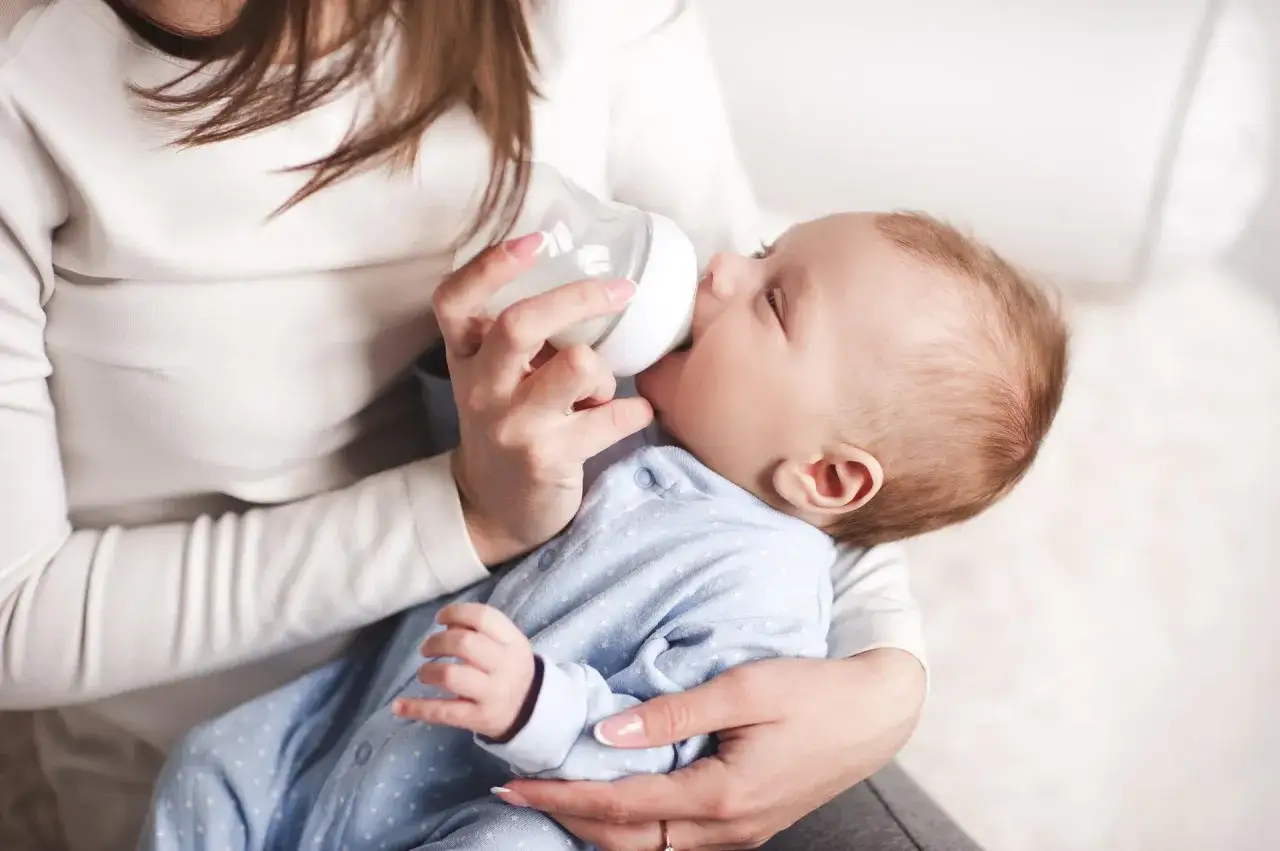Mama karmi butelką noworodka, pokazując jak karmic butelka noworodka.