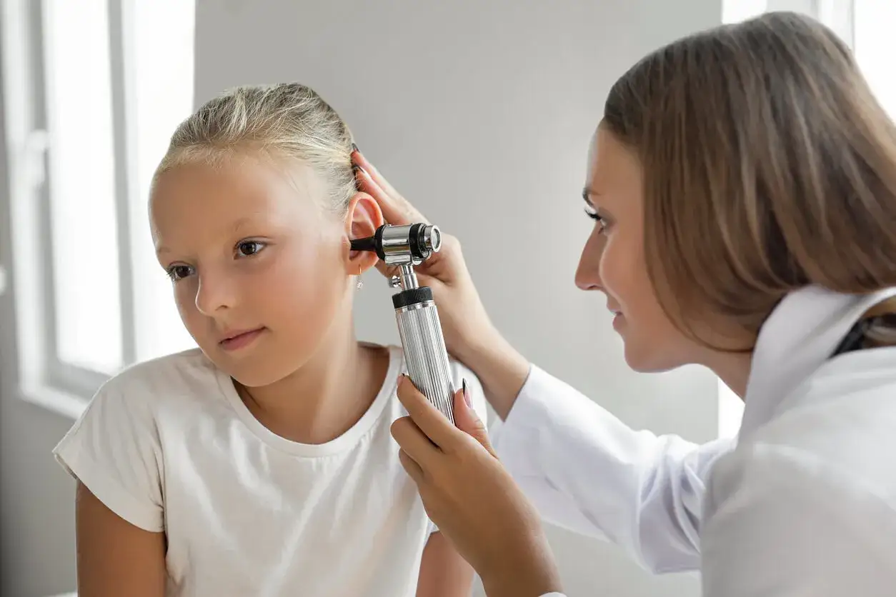 Lekarz bada ucho dziewczynki otoskopem. Szybka diagnoza zapalenia ucha i przepisanie 3 dniowego antybiotyku na zapalenie ucha.