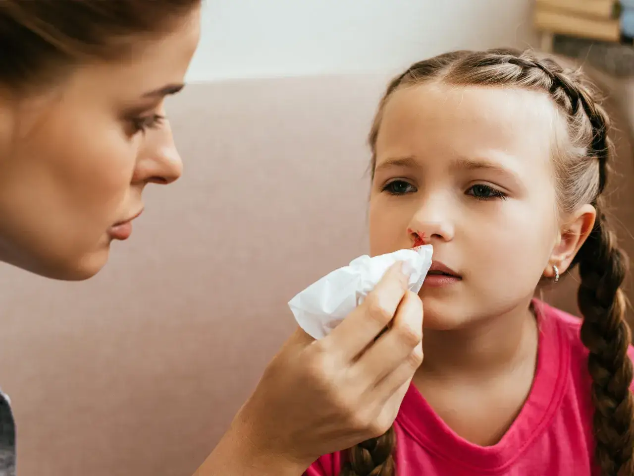 Mama delikatnie przemywa dziecku nosek, na kt&oacute;rym pojawiła się krew z nosa.